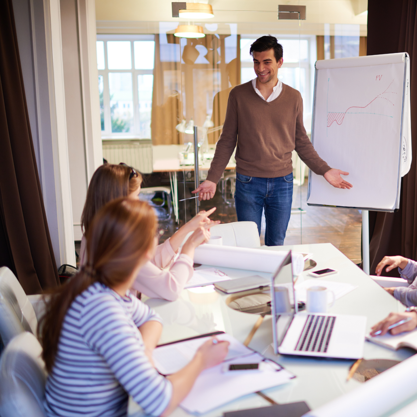 Un homme présente des idées à un groupe lors d'une réunion autour d'une table.