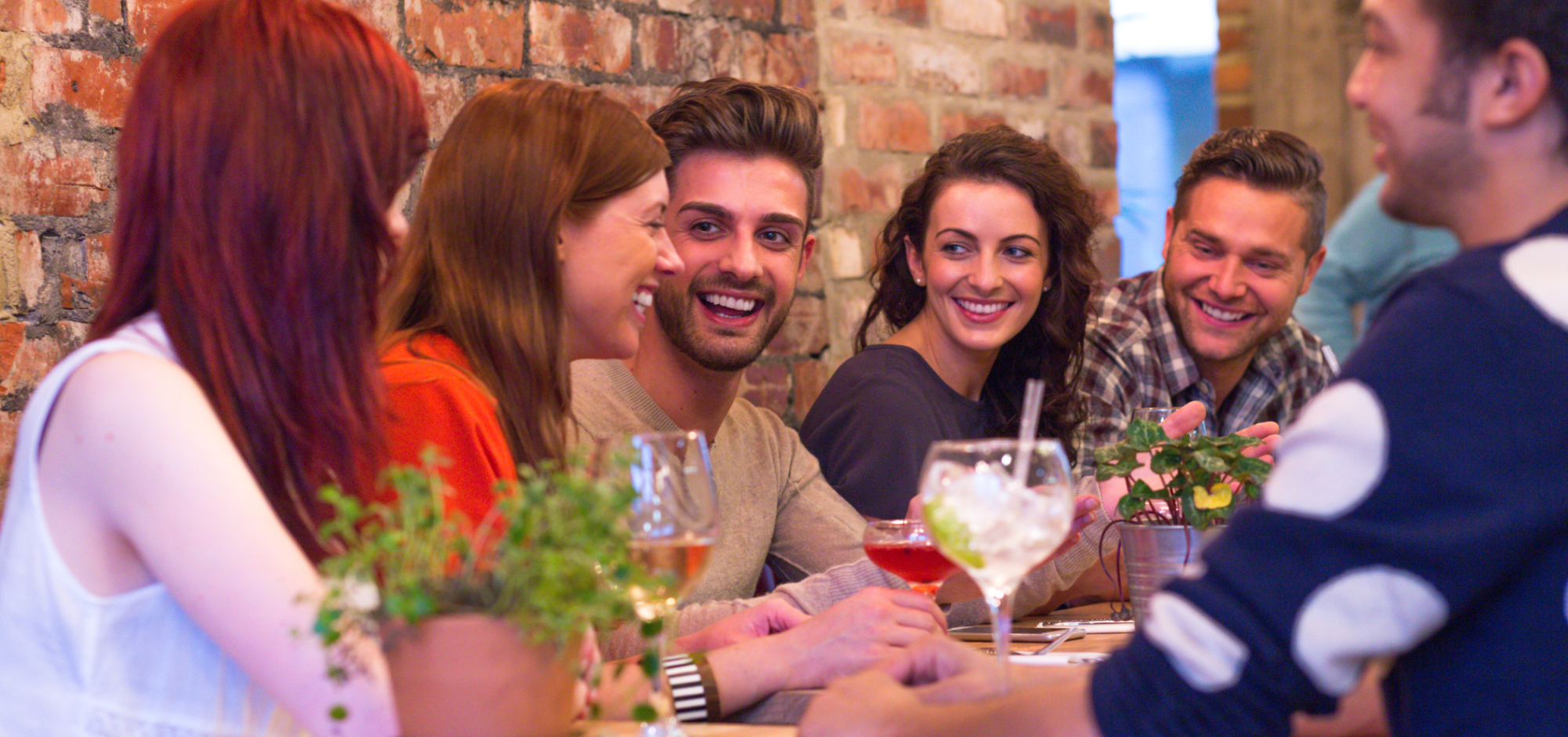 Groupe d'entrepreneurs souriants autour d’une table, partageant des boissons et des conversations.